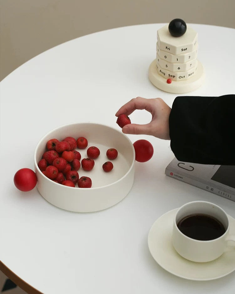A white ceramic decorative bowl with red accents designed for serving snacks or as a decorative piece from Untable