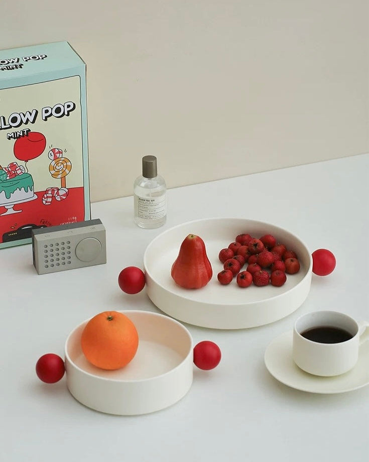 A white ceramic decorative bowl with red accents designed for serving snacks or as a decorative piece from Untable