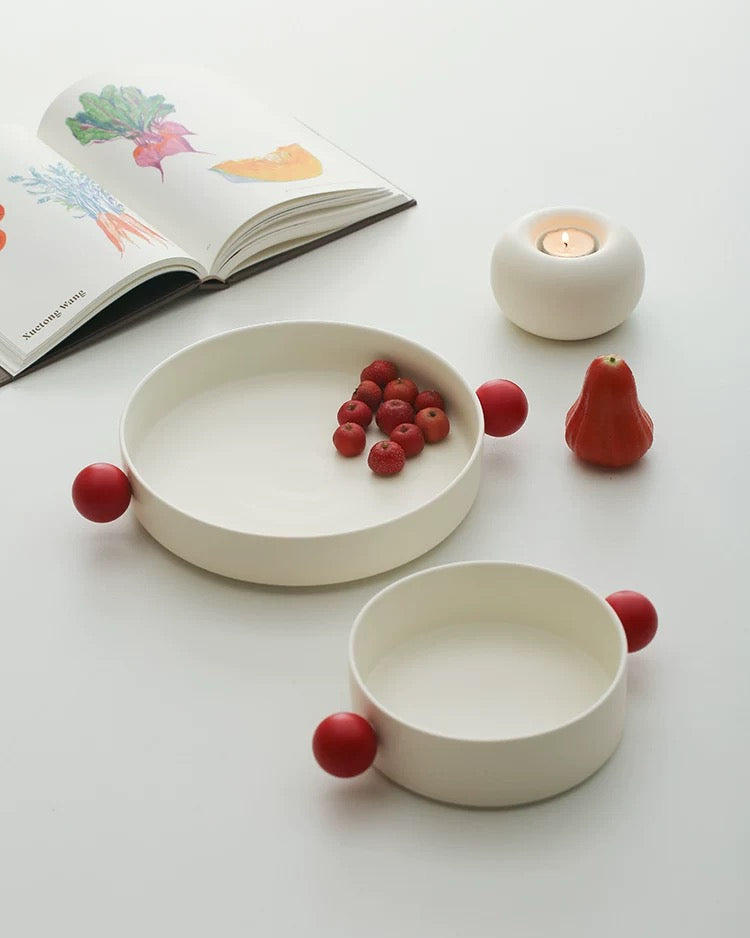 A white ceramic decorative bowl with red accents designed for serving snacks or as a decorative piece from Untable